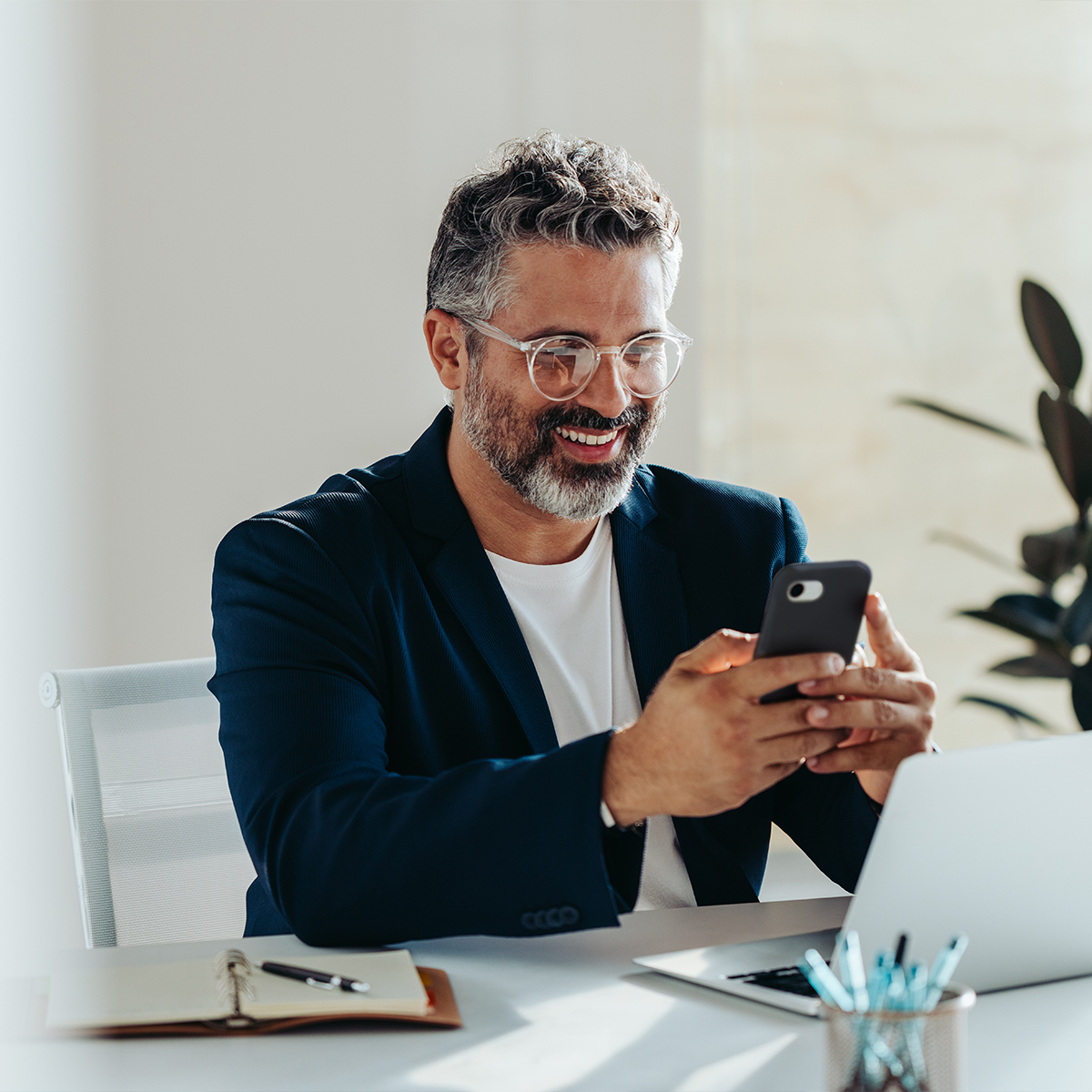 A professional adult male businessman is diligently working on his laptop at his office desk.