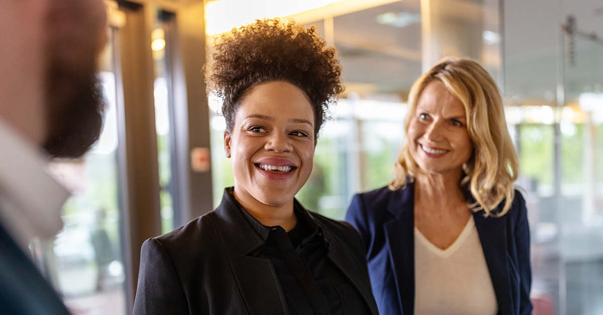Two successful businesswomen are happily collaborating on a project, exemplifying female partnership.